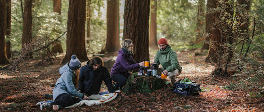 A group making coffee in the forest, in jackets